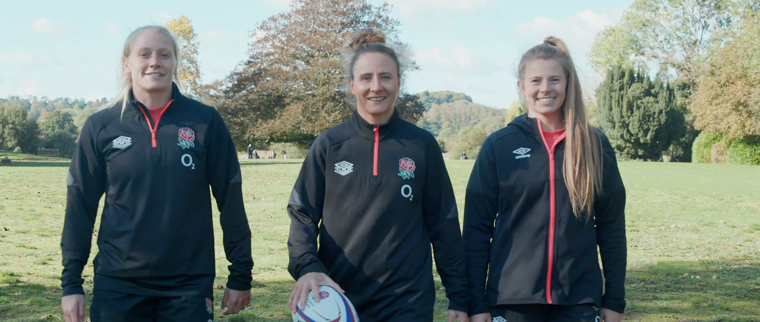 Three members of the Red Roses rugby team walking across a field.